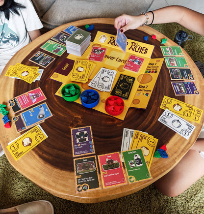 People playing a card game around a wooden table with colorful cards and game pieces.