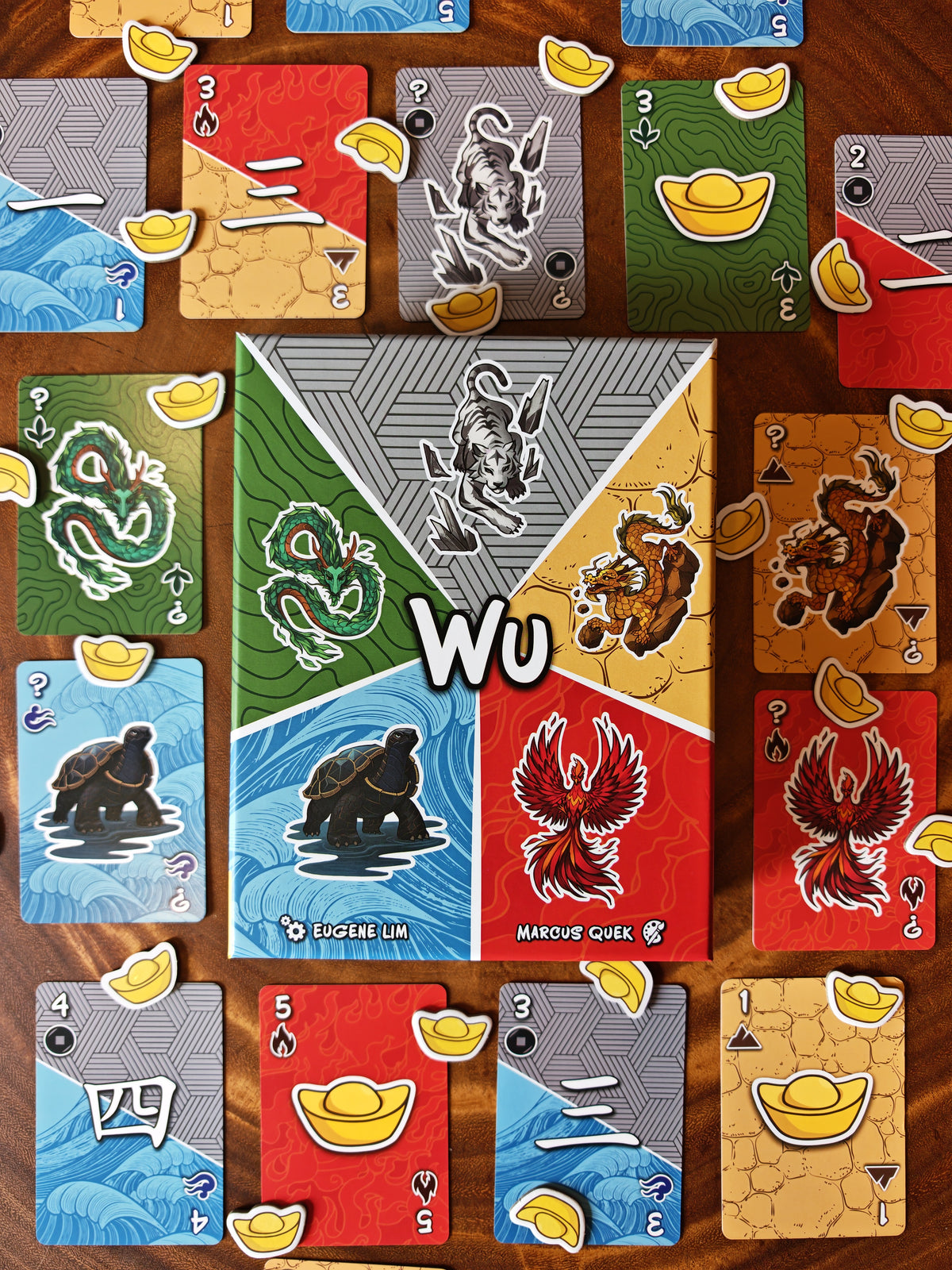A top-down shot of Wu's box and components, featuring its vibrant card designs and gold ingots.